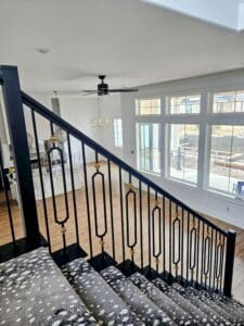 Staircase with black handrails leading down into living room