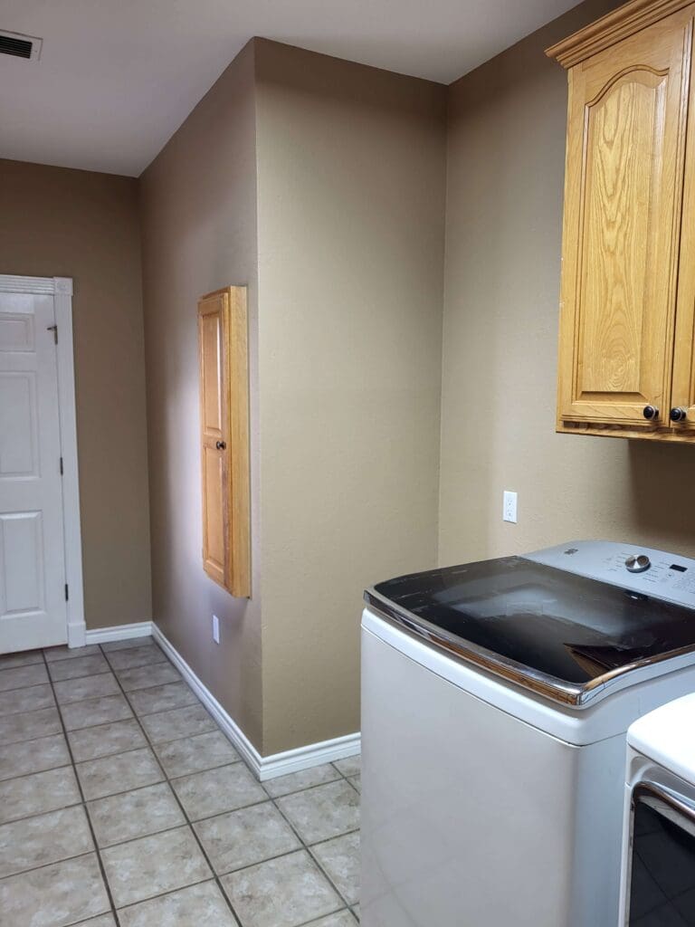 A laundry room with grey walls, a cabinet, washer and dryer