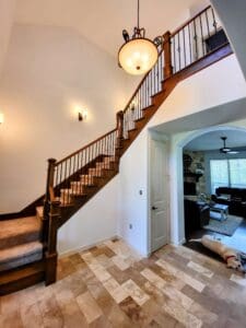 A spacious foyer with a wooden staircase and polished floors and white painted walls