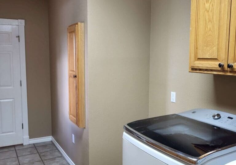 A laundry room with grey walls, a cabinet, washer and dryer